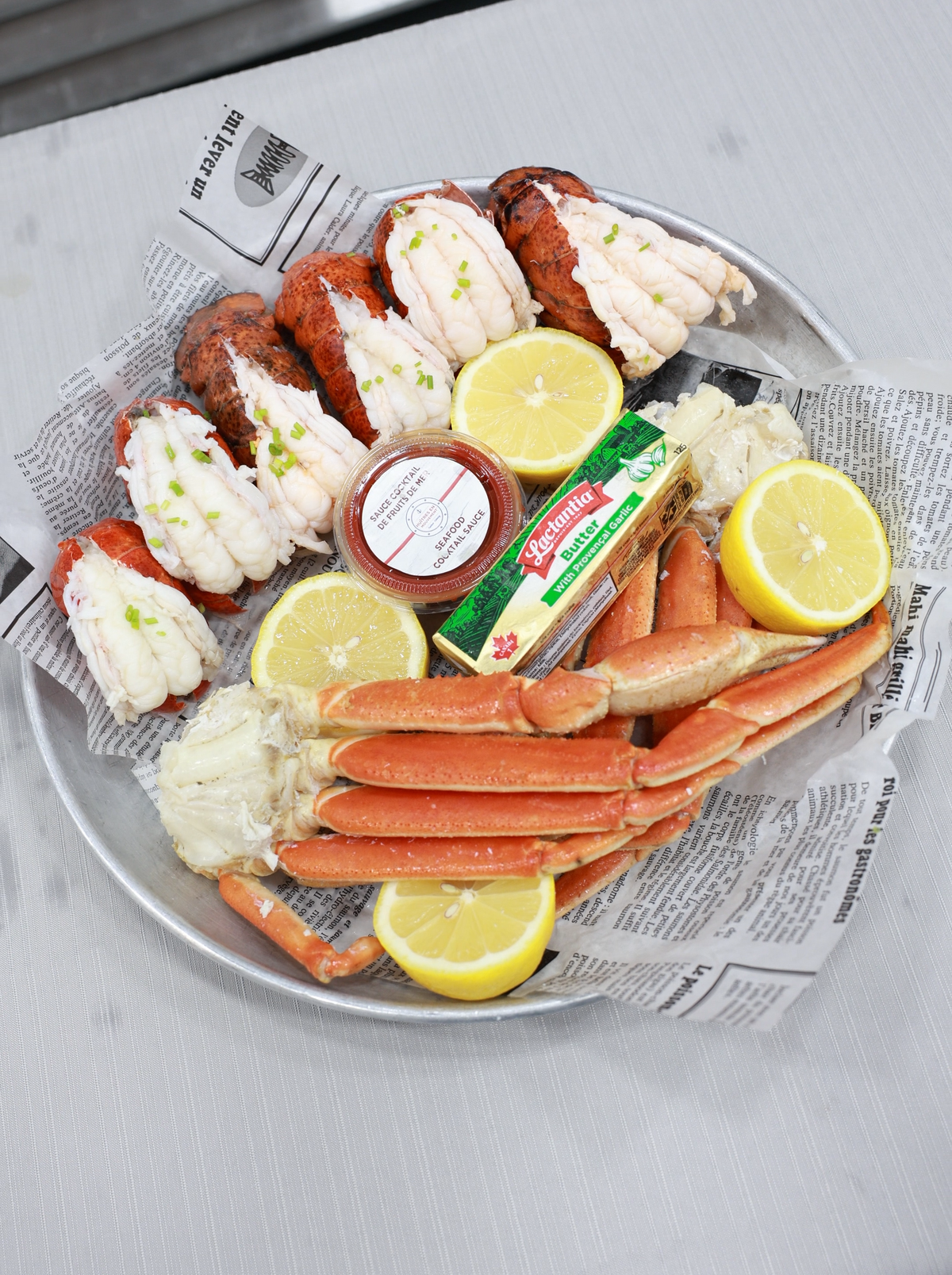 Romantic Lobster & Crab Feast for Two featuring lobster tails, crab legs, lemons, and dipping sauce on a platter.